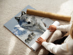 A woman is carefully rolling a fine art poster paper of a wolf print. The fine art paper enhances the artwork's detail and quality. This winter animal wall art is perfect for any nature lover. It brings a touch of the wild into your home.