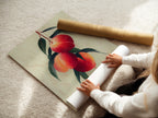 A woman carefully handles a fine art poster paper. She is preparing a peach fruit botanical wall art. This art is perfect for adding a touch of nature to your kitchen decor. The fine art paper ensures vivid colors. This is a beautiful addition to any farmhouse style artwork collection.