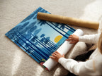 A woman carefully rolling a fine art poster paper. Preparing a tropical beach artwork for your home decor. This coastal seascape wall art features indigo blue and gold colors. Perfect for adding a touch of island art to your living room or bedroom. Ideal for homeowners and interior decorators.