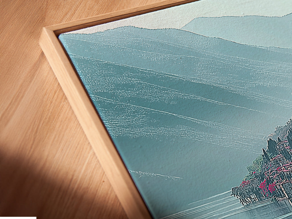 Close-up angled view of a Lake Como Italy canvas print in a floating frame. The floating frame gives the artwork a modern look. The teal mountain landscape is crisp and clear. A perfect piece of Italian coastal wall art. The lake view print brings serenity to any room. The scenic vista art is captivating.