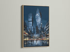 This showcases a modern city skyline art print with an oak frame. The urban wall art features a blue night cityscape. This piece is ideal for office decor. The oak frame adds warmth to the contemporary artwork.