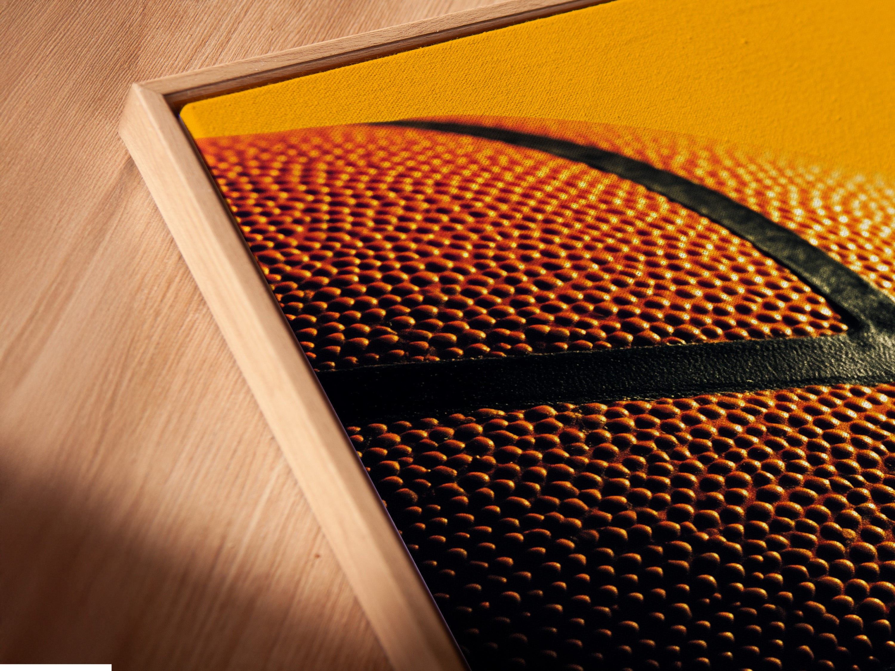 Angled close-up of a basketball canvas print in a floating frame. The floating frame adds depth to your artwork. The artwork makes a statement. Perfect for adding a modern touch to any room. Order yours today!