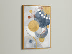 Modern geometric wall art in a gold frame brings elegance to your decor. The abstract artwork features blue and gold circles. This contemporary watercolor print is perfect for any room.