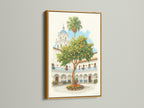 Spanish Courtyard artwork displayed in a gold frame. The artwork features a white building with a blue dome and an orange tree. The gold frame adds a touch of luxury. Display this beautiful Europe wall art in your vacation home.