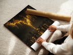 A woman is carefully rolling a fine art poster paper. This paper features the golden city skyline artwork. Ideal for creating urban canvas prints and abstract skyline art. The fine art poster paper ensures high-quality golden wall decor. Perfect for modern office art.