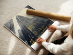 A woman carefully rolls a fine art poster paper. The paper showcases a cityscape artwork. This urban skyscraper print is ready to be framed and displayed. Ideal for modern architecture enthusiasts and collectors of fine art.
