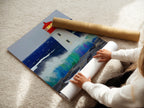 A woman carefully rolling a fine art poster paper of a lighthouse print. The fine art paper ensures high-quality reproduction. This coastal artwork is ready for framing or display. Perfect for adding a nautical touch. Seascape art.