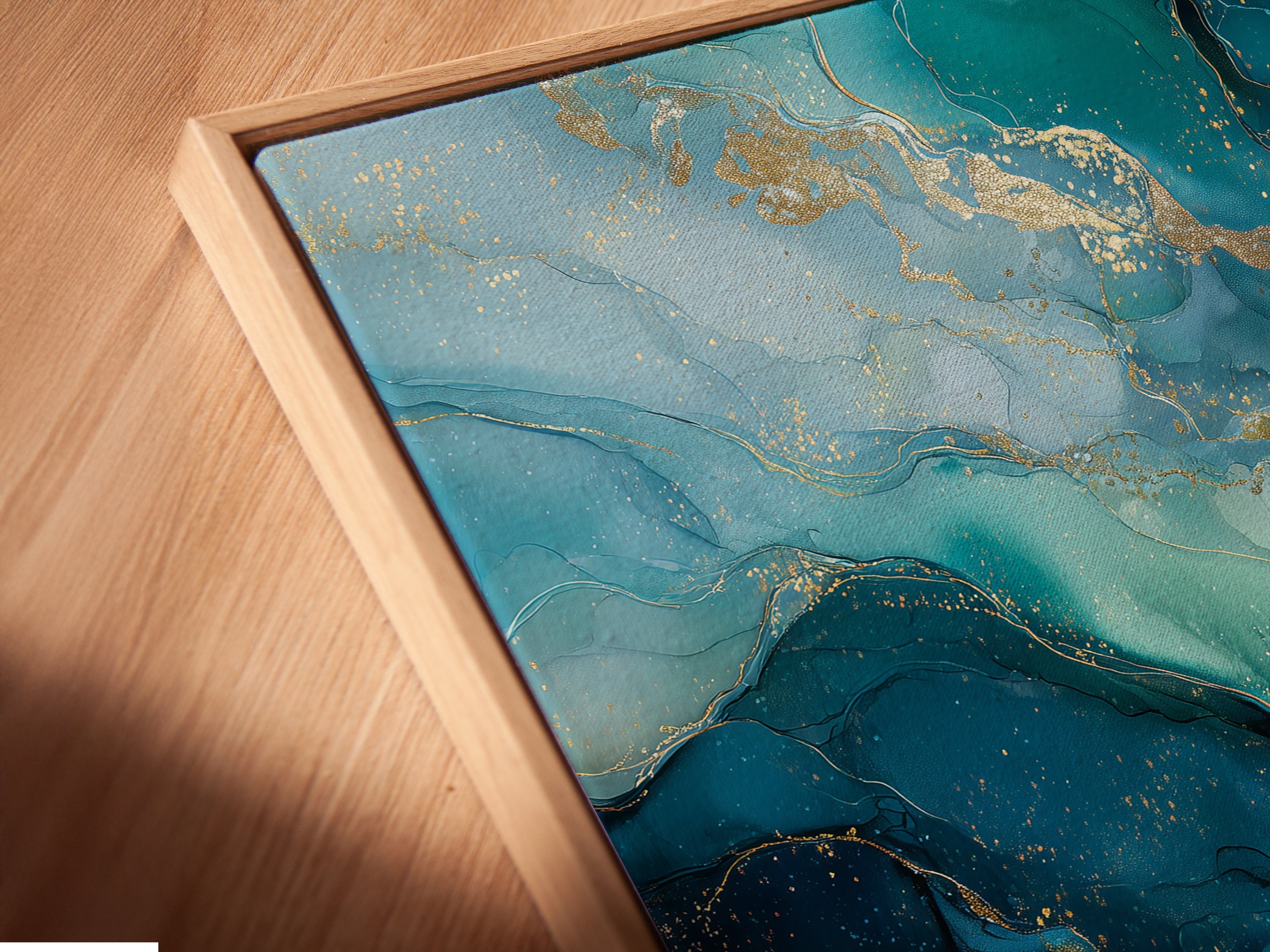 A close up angled view reveals an abstract ocean canvas print in a floating frame. The teal and gold artwork enhances modern bedroom decor. This fluid art poster adds a refined touch to coastal or eclectic interiors. A stylish addition to any space.