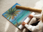 A woman rolling fine art poster paper featuring a tropical beach artwork. Palm tree coastal wall art creates a turquoise ocean painting for stunning wall decor. The artwork provides a soothing coastal vibe ideal for any interior. Perfect for art enthusiasts.