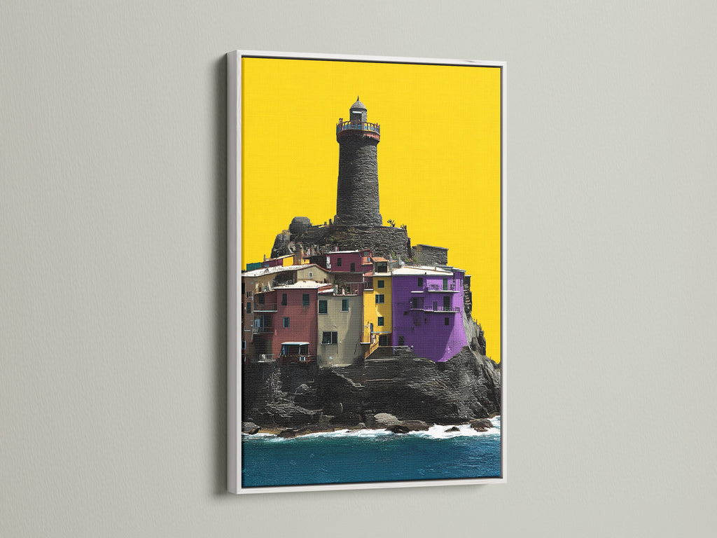 Coastal Lighthouse canvas artwork in a white frame. This piece showcases a colorful village with a lighthouse. It's great as modern wall decor. Add seaside charm to your home or office with this Italian art.