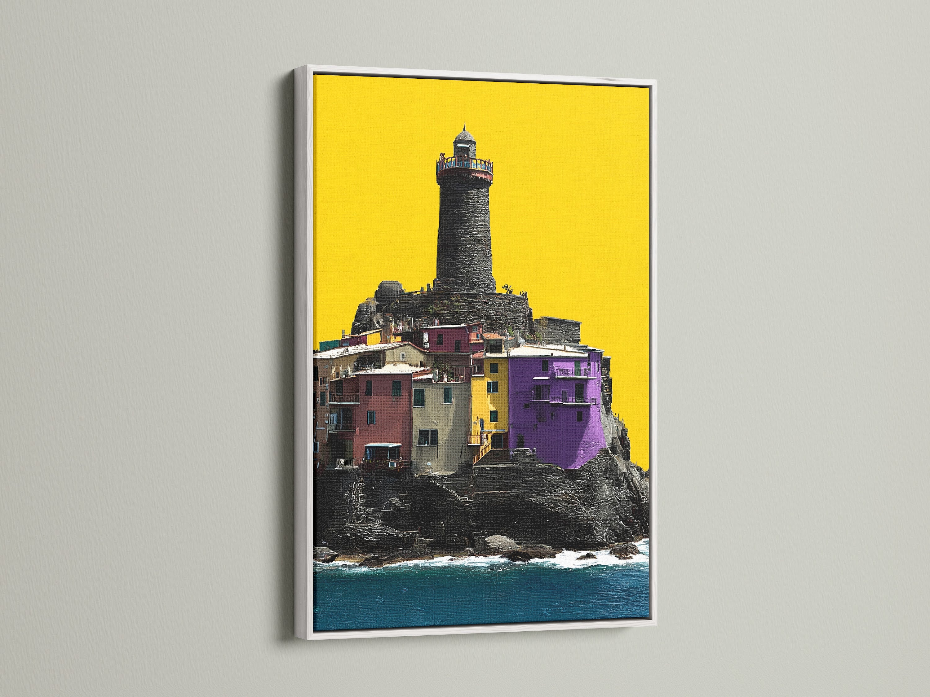 Coastal Lighthouse canvas artwork in a white frame. This piece showcases a colorful village with a lighthouse. It's great as modern wall decor. Add seaside charm to your home or office with this Italian art.