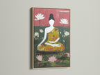 A framed meditation art piece with an oak frame hangs on a white wall. The artwork shows a seated Buddha amidst lotus blossoms. The print adds a touch of zen home decor to minimalist Scandinavian or eclectic spaces. Ideal for meditation rooms and wellness centers.
