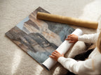 A woman carefully rolling a fine art poster paper print. The poster features a Canyon River desert landscape. This nature painting is perfect for art lovers. Fine art poster paper ensures high-quality prints. Shop now for Southwestern decor. Bring earth tone art into your home or office today.