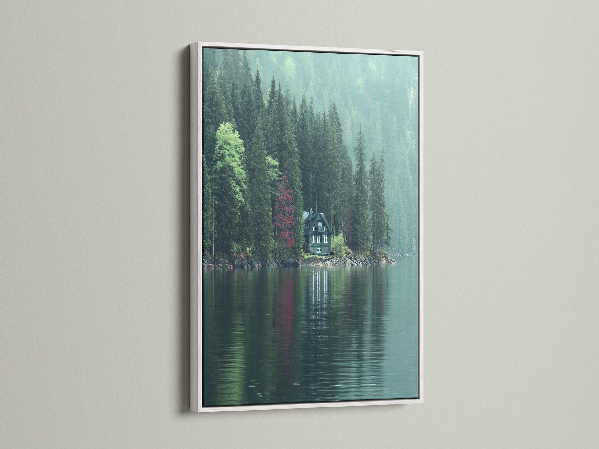 Lakeside Cabin artwork is presented with a white frame. The artwork shows a serene lake landscape with a cabin nestled among green pine trees. A red tree adds contrast. This nature print brings a touch of modern tranquility to any space. Perfect as living room wall art.