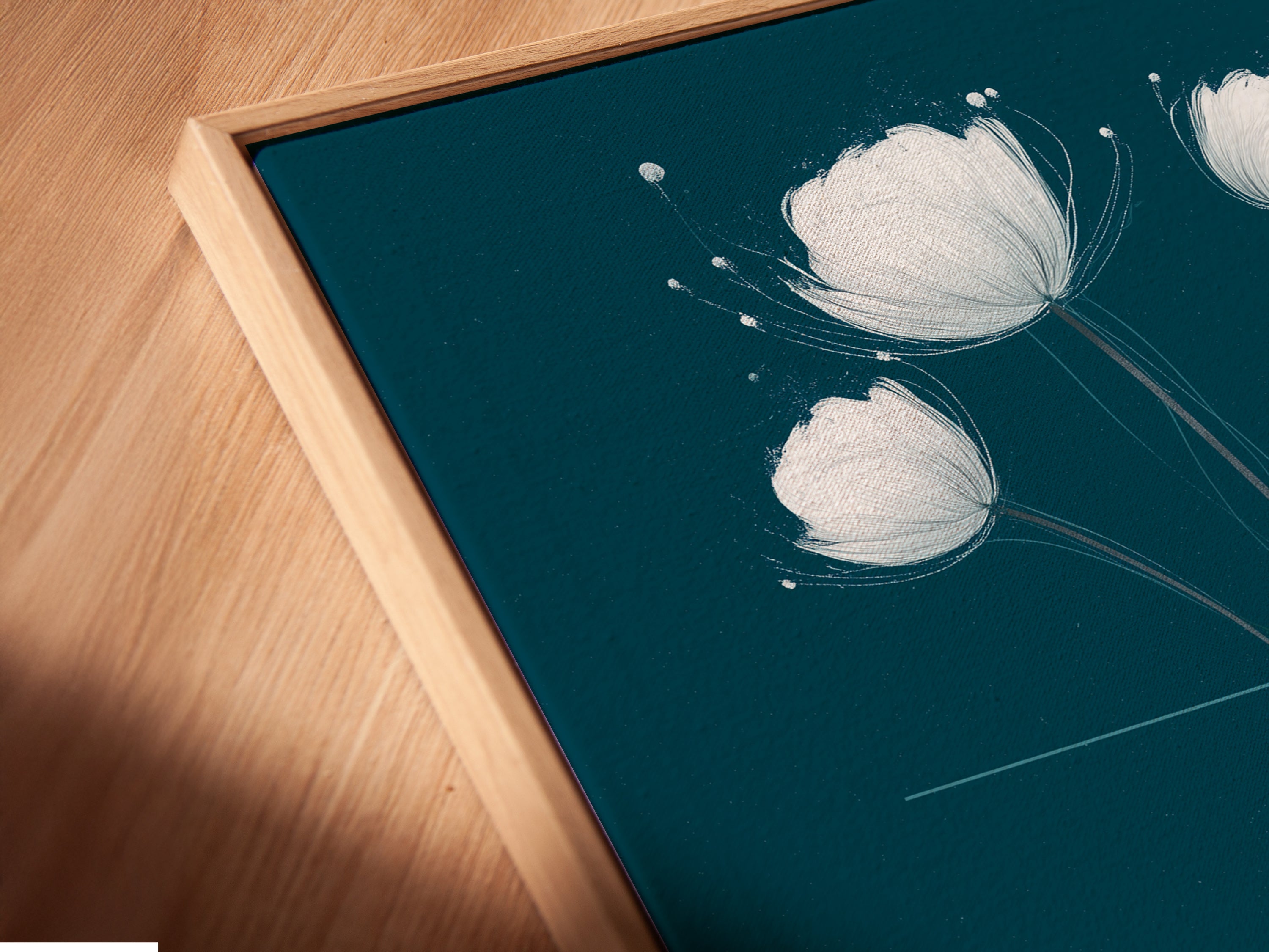 Angled close up of a white flower canvas print in a floating frame. The teal and yellow floral wall art adds a modern touch. This minimalist botanical art is perfect for a bedroom or living room. Enjoy this flower artwork.