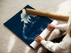 A woman rolls a fine art poster paper. This paper showcases the wolf silhouette. This navy blue nature artwork is ideal for creating wall art. Available as a stretched canvas print or floating frame.