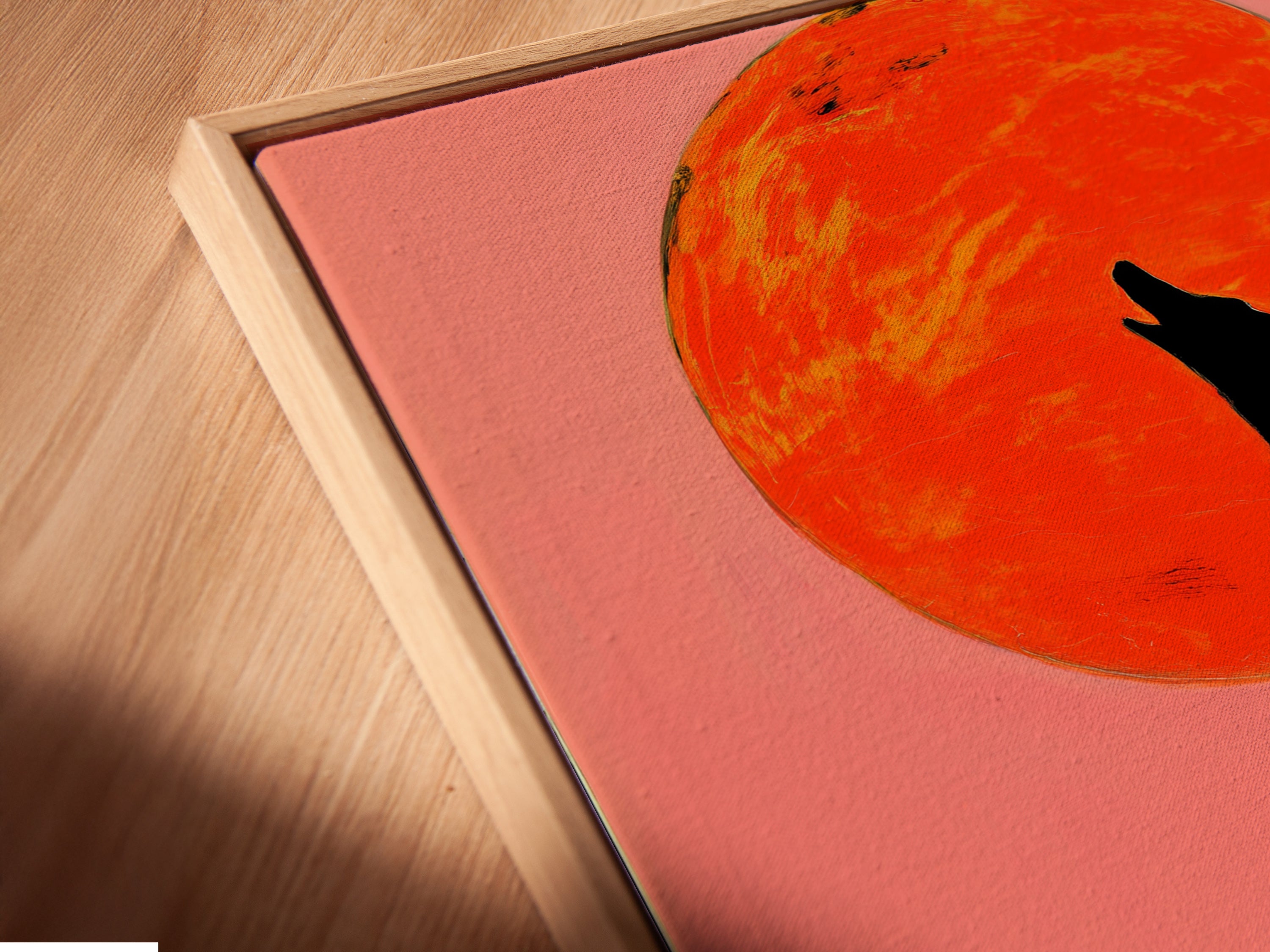 A close-up shows the Wolf Moon Canvas Print in a floating frame. The abstract wildlife art features a striking wolf silhouette. The colorful sunset print seems to float within the frame. This modern animal art adds a unique touch to your wall decor. Perfect for a contemporary style statement.
