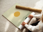 A woman is carefully rolling a fine art poster paper. This ensures safe handling of the desert landscape artwork. The artwork features warm earth tones. It is minimalist art. This print brings southwestern decor to a home or office. It creates a calming atmosphere.