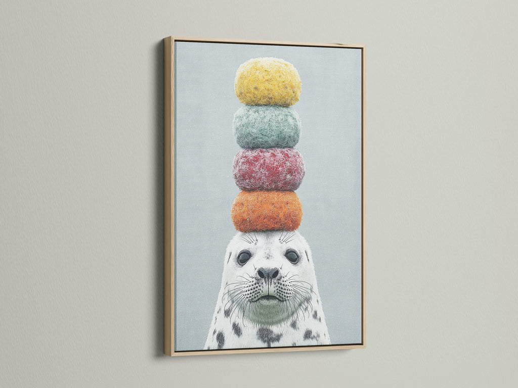 A close-up of a framed canvas print featuring a whimsical seal artwork. The art is framed in a natural oak frame. This colorful animal art adds a playful touch to any room. Ideal for kids rooms nurseries or anyone who loves marine life art.