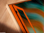 A close-up angled shot reveals a canvas print in a floating frame. Aurora Borealis artwork enhances this Nordic landscape wall art. The open window view brings teal and orange colors to life. Modern home art at its finest.