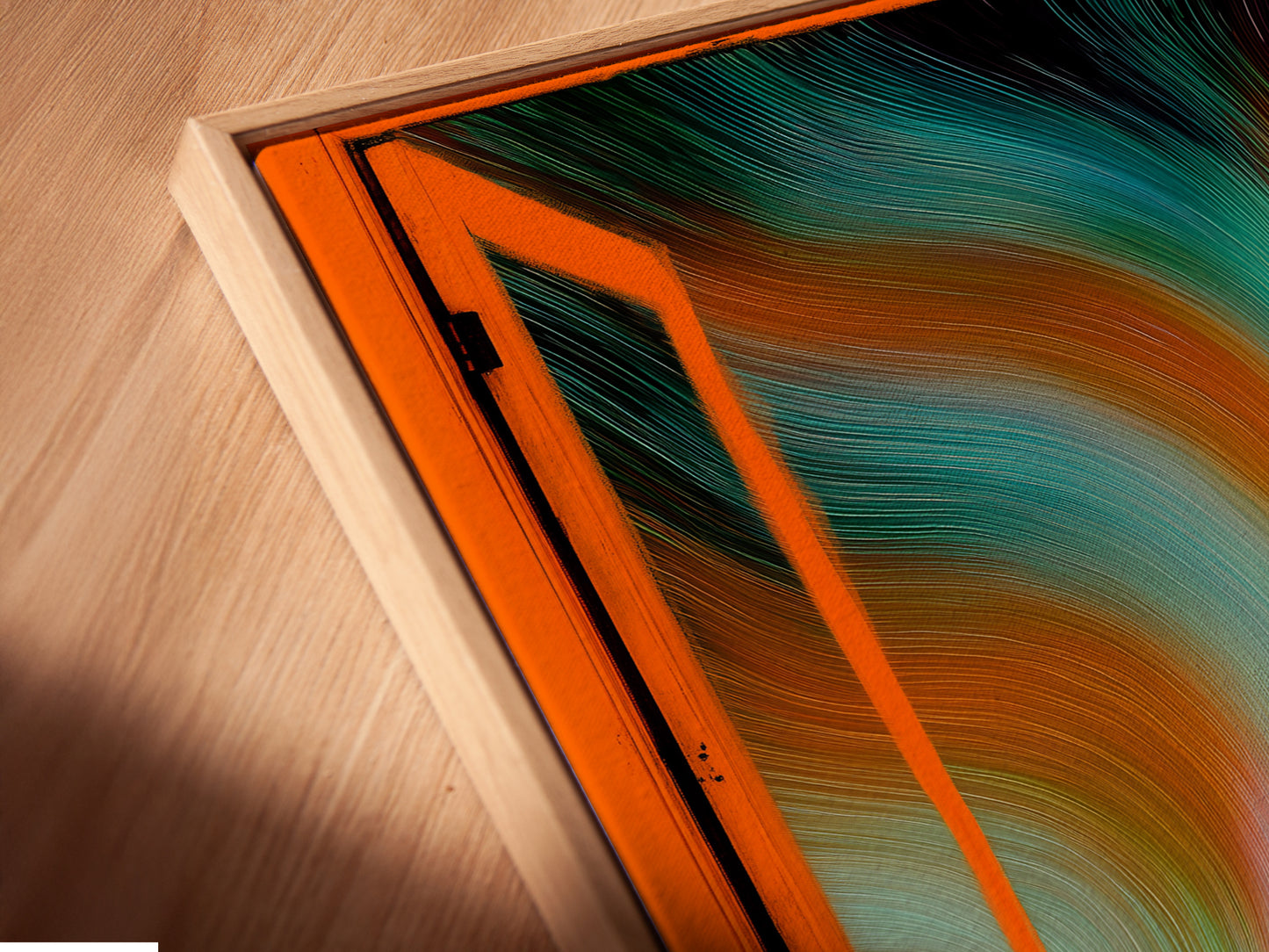 A close-up angled shot reveals a canvas print in a floating frame. Aurora Borealis artwork enhances this Nordic landscape wall art. The open window view brings teal and orange colors to life. Modern home art at its finest.