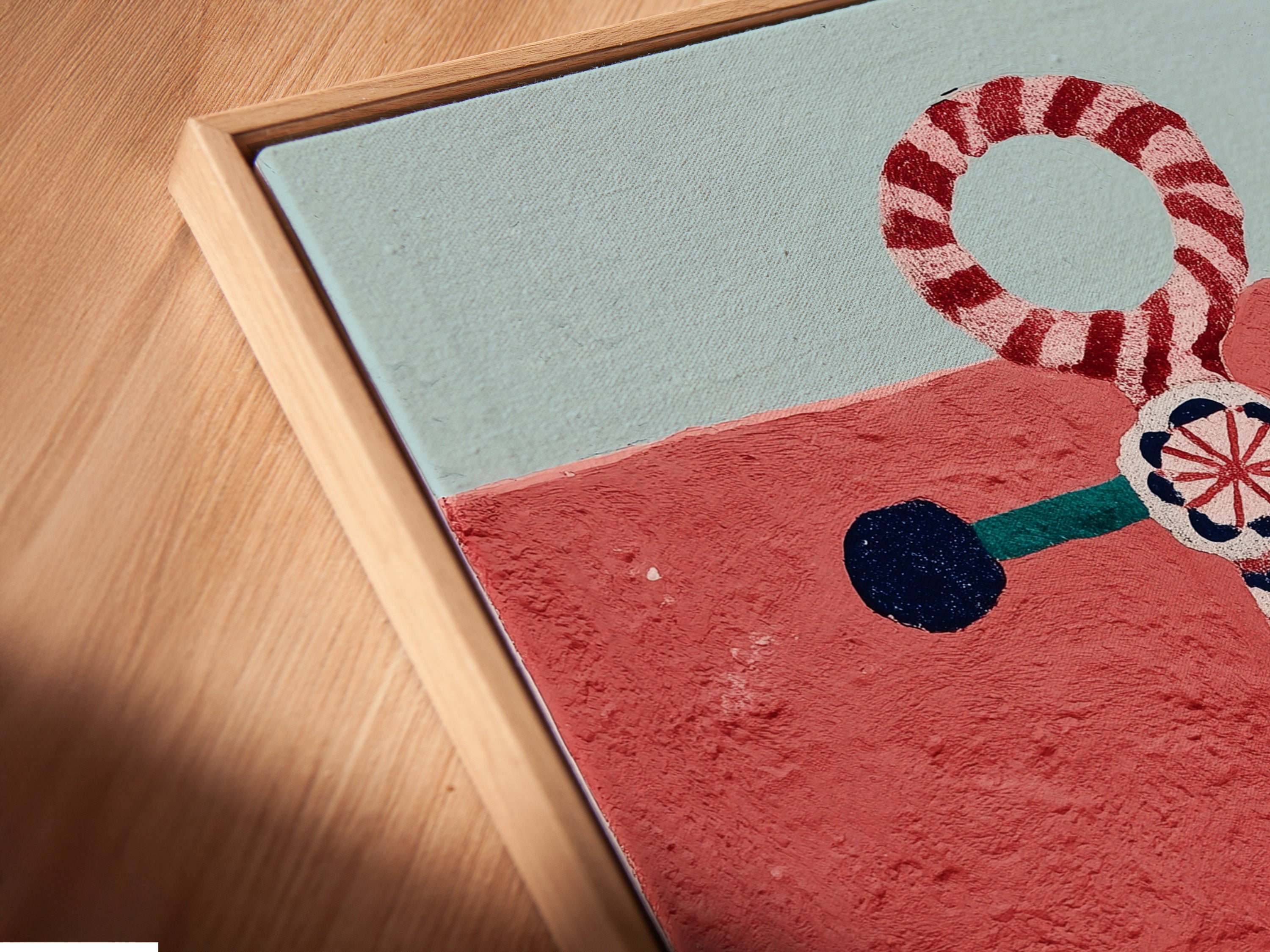 Angled close up of a canvas print in floating frame. The anchor artwork features red and teal hues. This nautical wall art is perfect for coastal decor. The seaside artwork enhances any space. Ideal for bathroom art and living room decor. Bring the beach home with this ocean canvas.