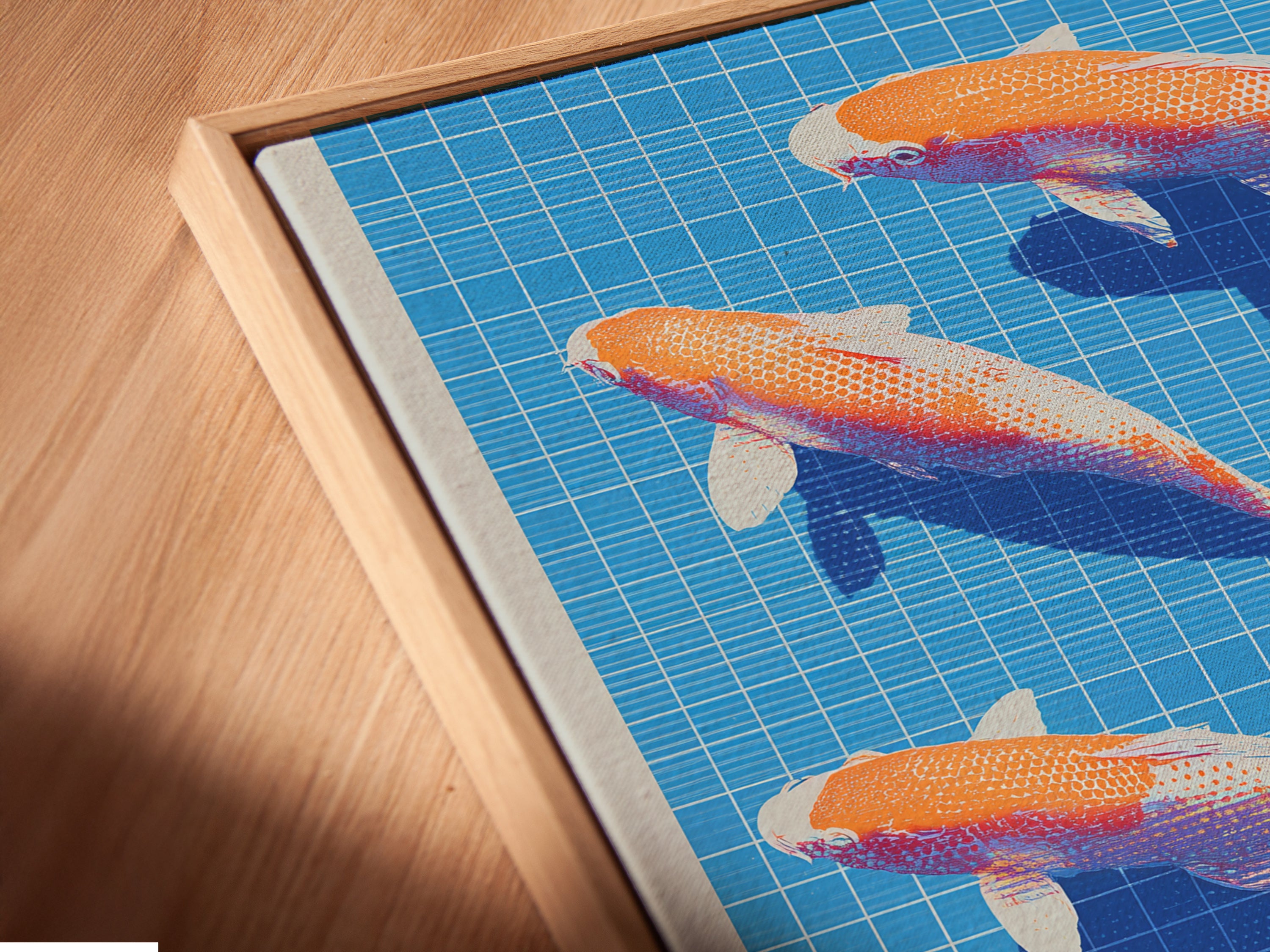 Angled close-up of a canvas print in a floating frame. The Koi Fish artwork features a blue grid background with orange and white fish. This modern art print is ready to hang in living rooms bedrooms or offices.