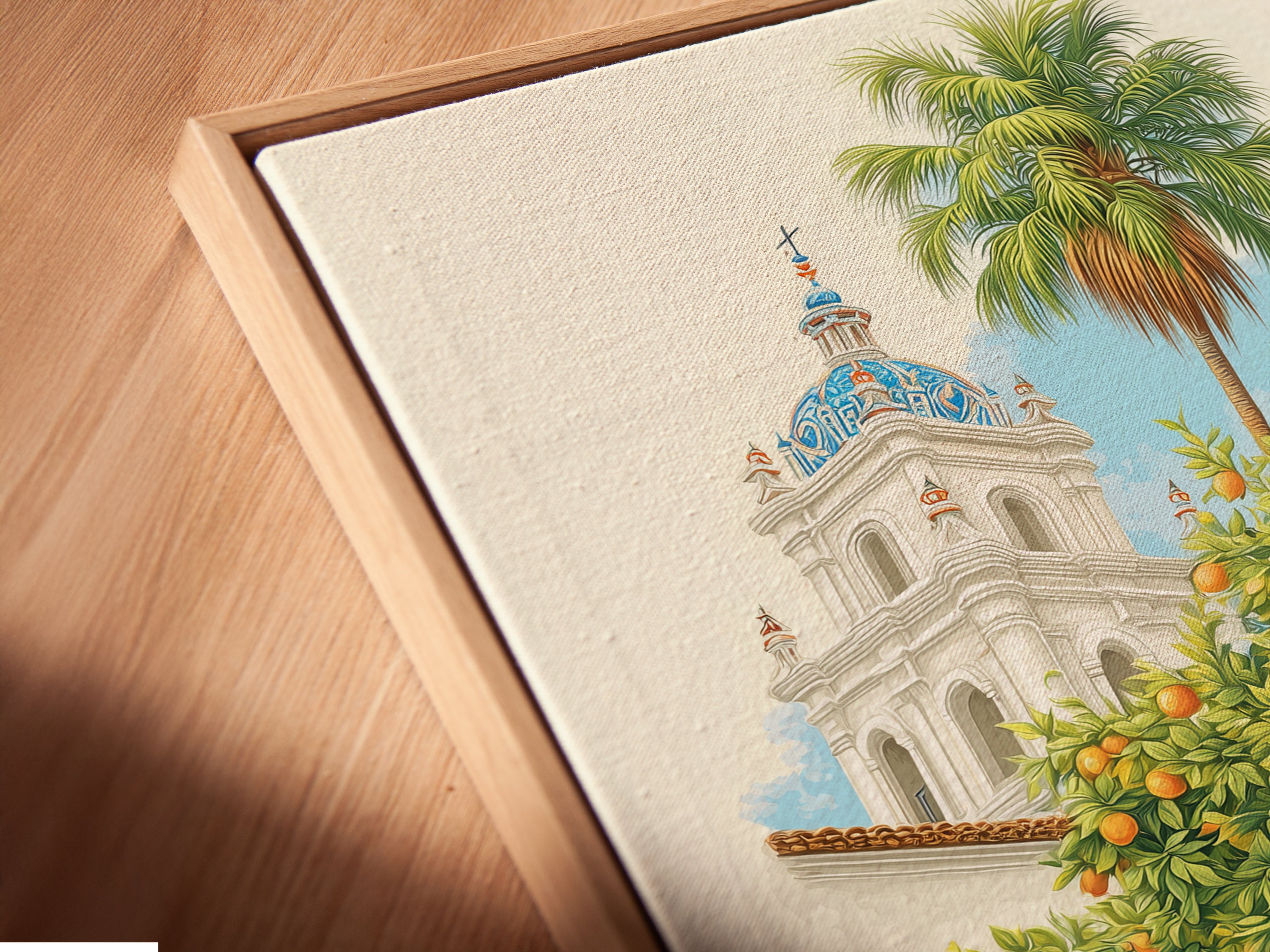 A close-up angled view of the Spanish Courtyard canvas print in a floating frame. The floating frame gives the artwork a modern and sophisticated look. This print features a white building with a blue dome and an orange tree. Great way to showcase your artwork.