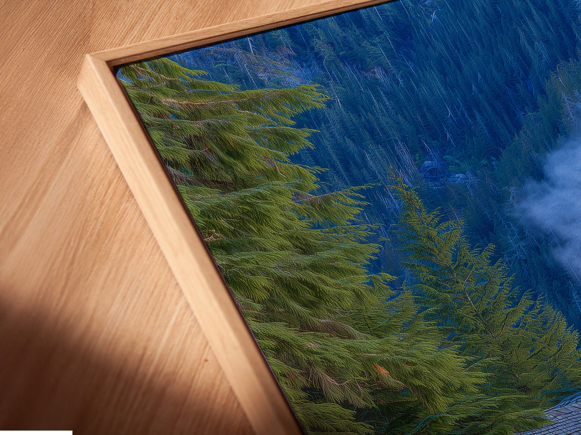 A close-up angled view showcases a canvas print in a floating frame. The artwork features a cozy mountain lodge nestled among pine trees and blue flowers. The floating frame enhances the artwork creating a sophisticated display. Perfect rustic decor for your living space.
