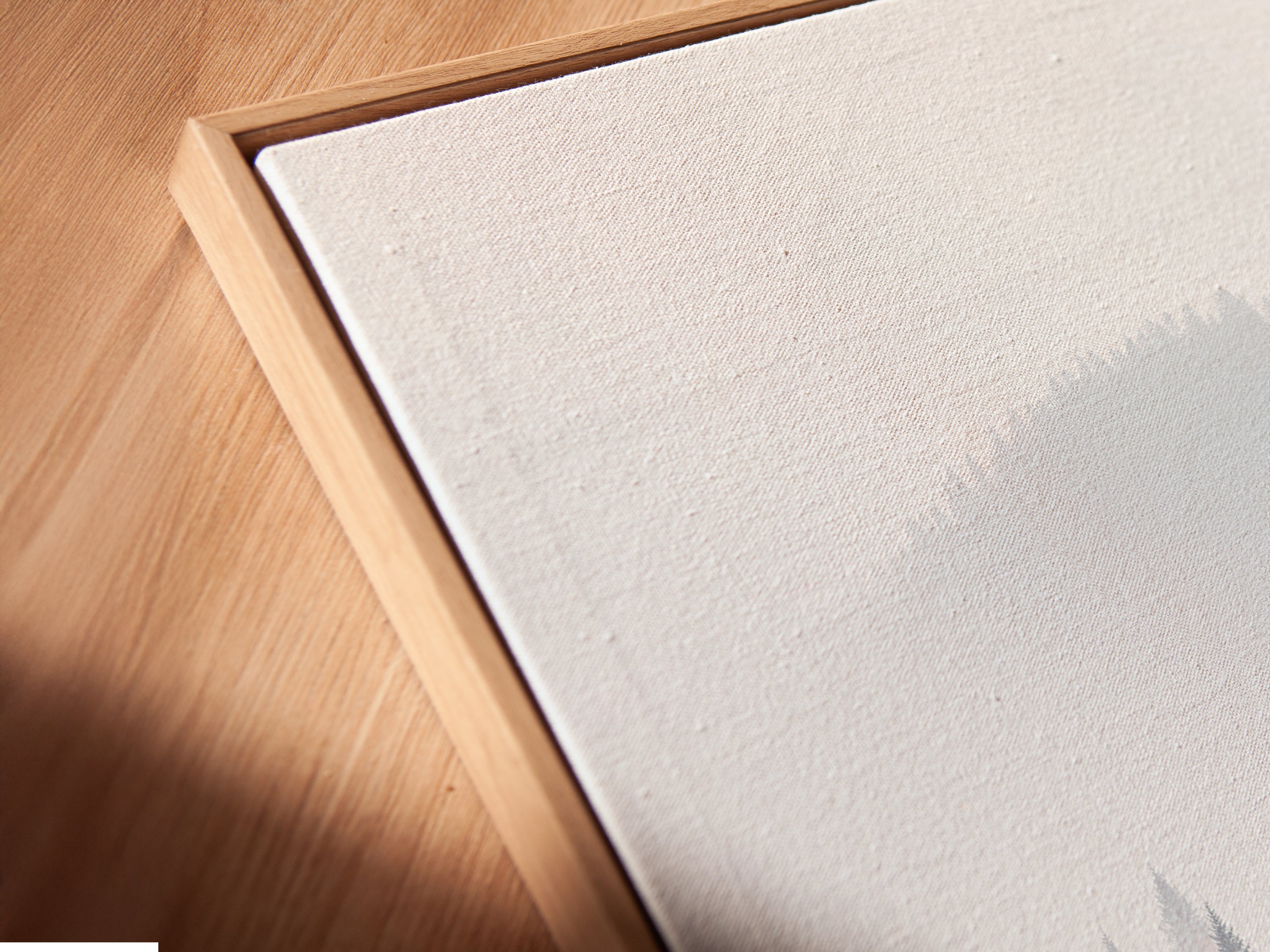 A close-up angled view shows a canvas print in a floating frame. This modern artwork features misty mountains and evergreen trees. This piece enhances any space with natural beauty. Great for contemporary decor in homes and offices. Explore now.