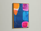 Abstract Geometric Print in a Gold Frame. The modern canvas art features a navy blue background with geometric shapes in pink orange and blue. Elevate your office wall decor with this vibrant art print. This abstract artwork is perfect for contemporary spaces