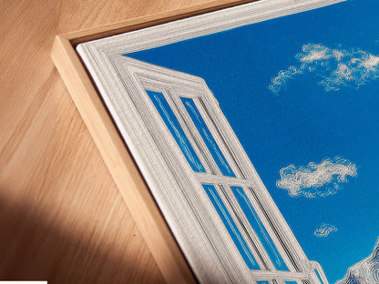 A close-up of a canvas print in a floating frame. The artwork showcases a mountain view. The print features a bright blue sky with fluffy clouds. A snow-capped mountain is seen through an open window. This artwork is modern. 