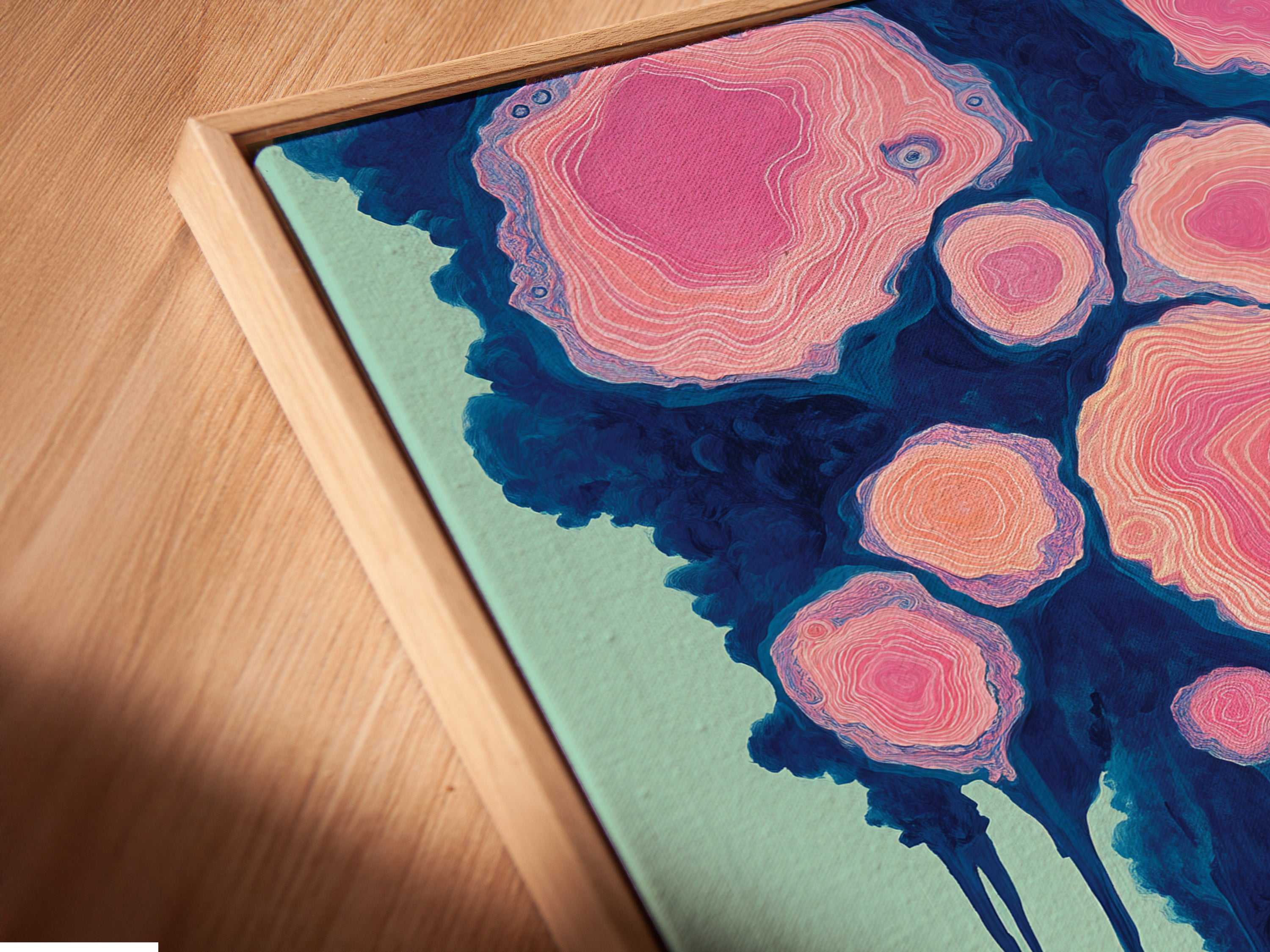 A close up of our canvas print in a floating frame. The artwork features a surreal landscape with a dreamy pink cloud forest. The contemporary style complements any space. See the depth and texture of this abstract nature art. This art piece is perfect for homeowners and apartment dwellers seeking refined decor.
