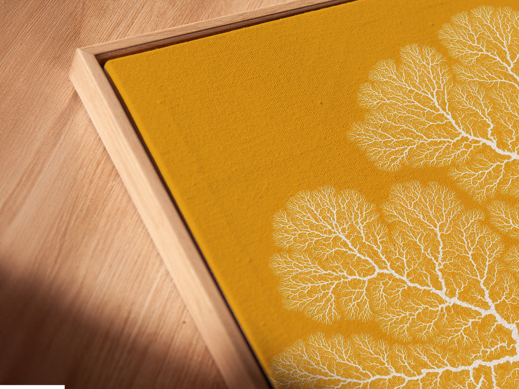 A close-up of a canvas print in a floating frame. The abstract coral artwork is ochre yellow. This coastal botanical artwork enhances any room. Perfect for living room wall art. This contemporary print adds sophistication to your space.