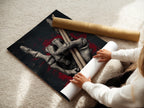 A woman is carefully rolling a fine art poster paper print of the Skeleton Hand Drumsticks artwork. This gothic art is perfect for music enthusiasts. The poster is ideal for framing and displaying in music rooms. It adds a touch of dark academia to any space.