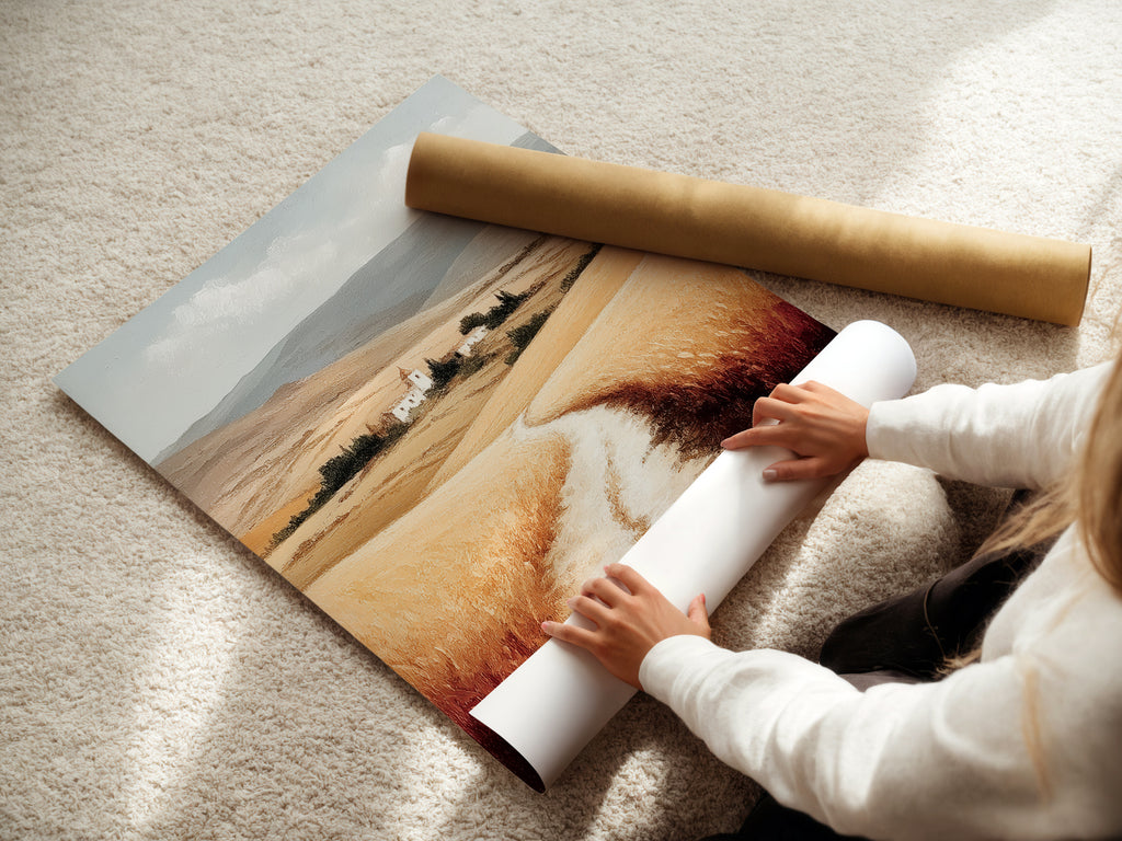 A woman is carefully rolling a fine art poster paper featuring a Tuscan Landscape. This Italy art print is perfect for farmhouse decor. The neutral tone art captures the Italian scenery. Featuring wheat field art this piece adds a touch of Europe to your walls. Ideal for rustic wall art.