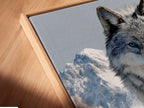 Angled close-up reveals a canvas print in a floating frame. A wolf pack artwork is featured in this animal wall art. The winter landscape shows a mountain scenery. Cabin wall decor is elevated by this nature-inspired artwork.