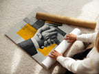 A woman is carefully rolling a fine art poster paper of the Business Handshake Art Print. The print is a modern corporate artwork. It features yellow abstract design. This high-quality poster is perfect for office wall decor.