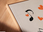 Close-up angled view of a canvas print in a floating frame. The origami cranes artwork is visible. It features two origami cranes on a music sheet background. The floating frame gives a modern touch.