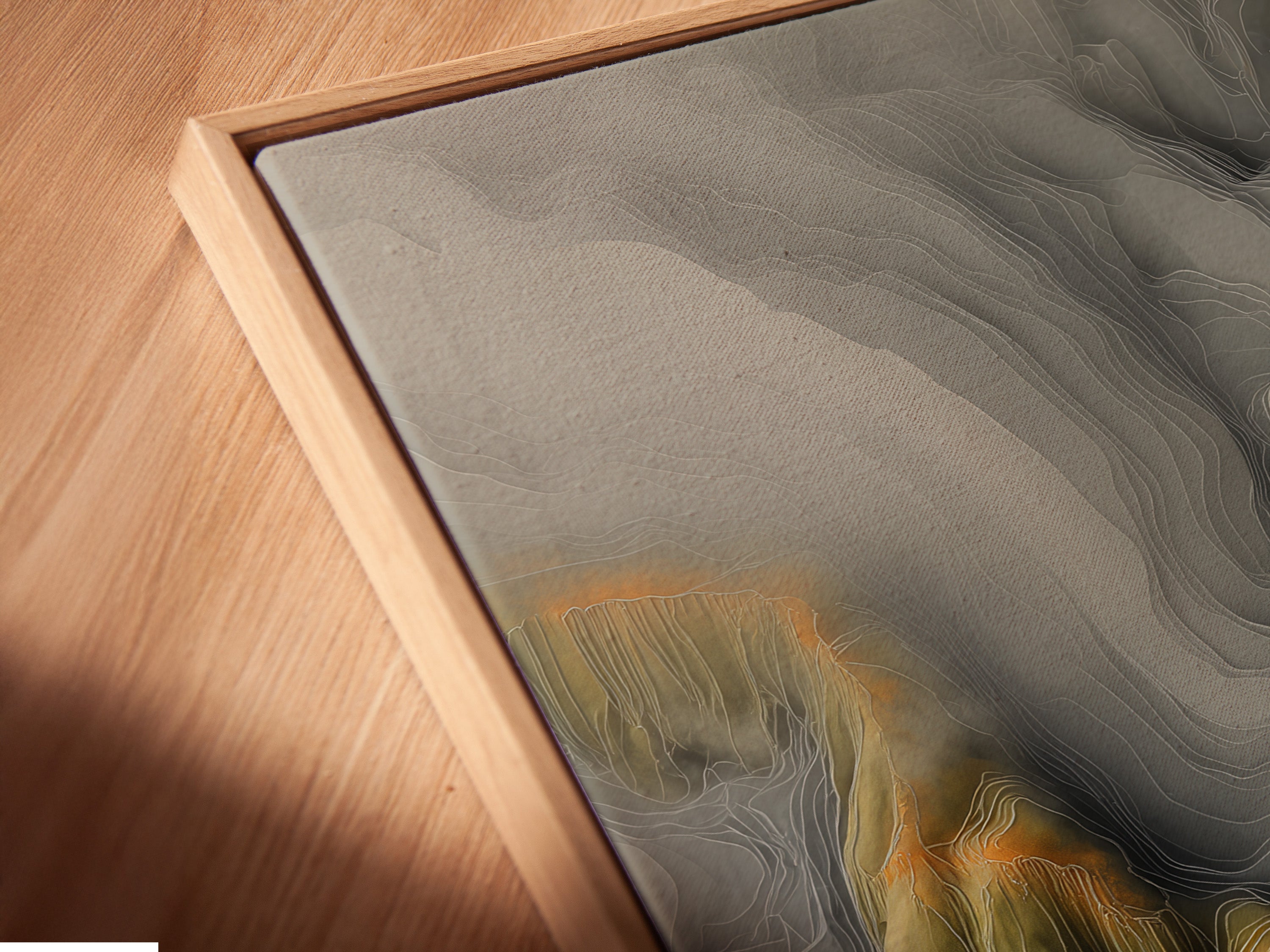 Angled close up of a canvas print in a floating frame. The artwork features a topographical map. The floating frame adds depth. It creates a modern aesthetic. This view highlights the texture. It shows the quality of the print.