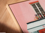 Angled close-up of a canvas print displayed in a floating frame. The artwork features a bakery with a pink exterior and blue accents. The floating frame enhances the art. It creates a modern and elegant look. This piece will add a contemporary touch to your space.