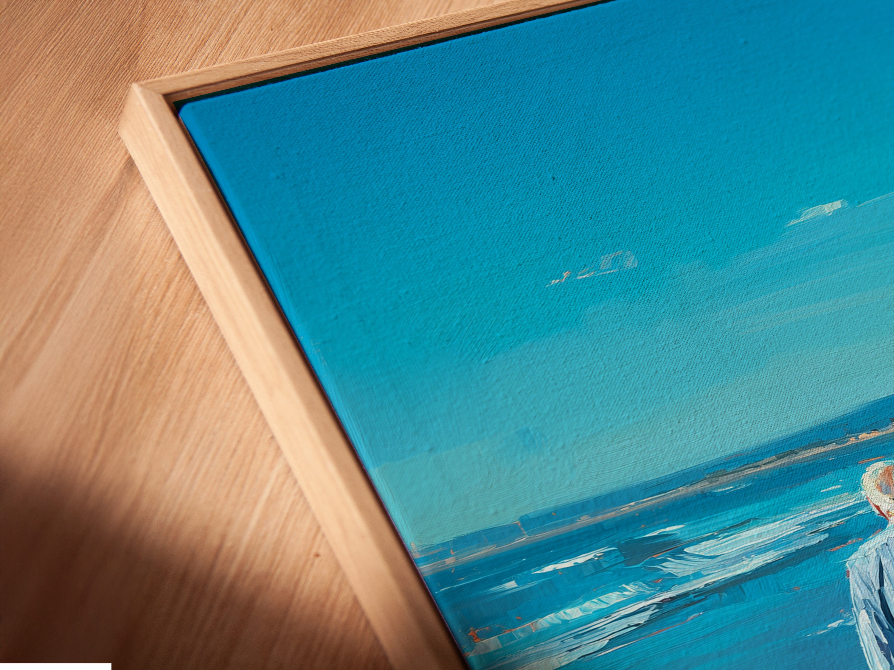This is a close-up angled view of a canvas print in a floating frame. The frame enhances the artwork's visual appeal. The art features a man and child walking on the beach. The canvas print adds texture and depth to the artwork. The floating frame provides a modern aesthetic.