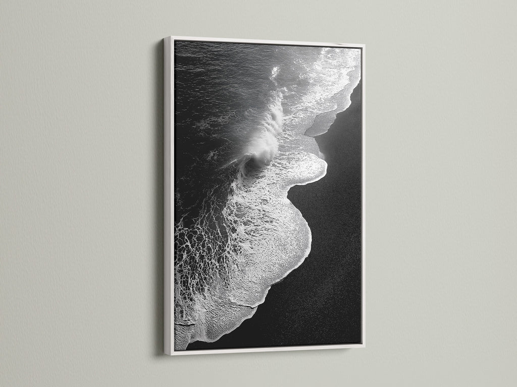 This artwork is a black and white ocean wave print. It is framed in white. It provides a clean and minimalist aesthetic. This beach canvas print brings coastal charm. It's perfect for creating a serene atmosphere. Ideal for bedroom decor and coastal retreats. Explore ocean photography with this stunning piece.