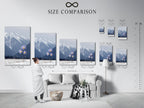 A size comparison chart is shown in an interior setting. View the various sizes available for the mountain flower canvas print. This winter landscape art can transform any space. Choose the perfect size for your snowy peak wall decor.