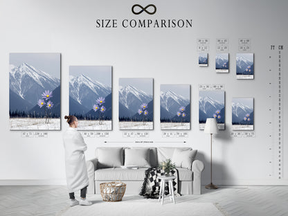 A size comparison chart is shown in an interior setting. View the various sizes available for the mountain flower canvas print. This winter landscape art can transform any space. Choose the perfect size for your snowy peak wall decor.