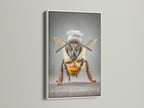 A white frame surrounds Chef Bee artwork. This adds a clean modern look. It's a quirky bee print that brightens any kitchen. It's whimsical decor for dining rooms. The white frame complements contemporary styles.