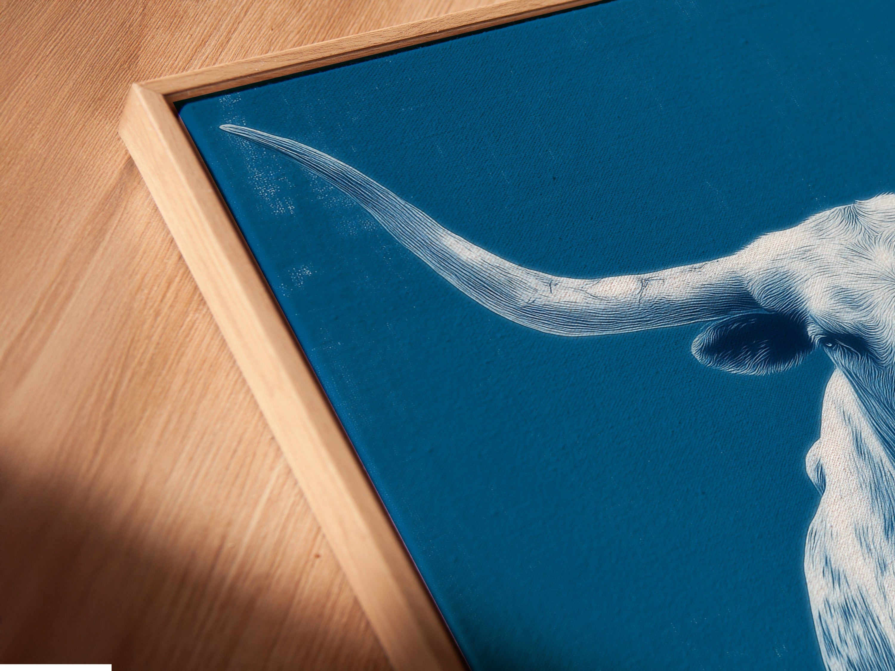 A close up of the canvas print is displayed in a floating frame. The longhorn bull artwork is a stunning piece of western ranch wall art. The floating frame adds a modern touch. Enhance your living room with this.