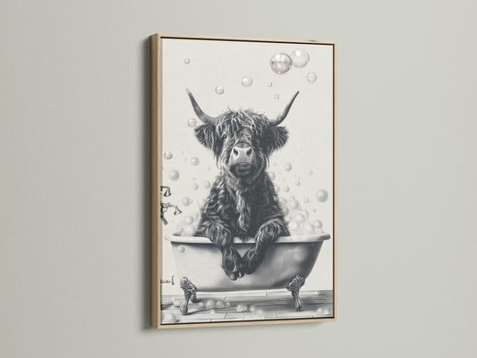 A close up of a wall featuring a framed Highland Cow art print. The artwork features a black and white image of a cow relaxing in a bathtub filled with bubbles. The frame is a light oak color. It complements Country Farmhouse style bathroom art or wall decor.
