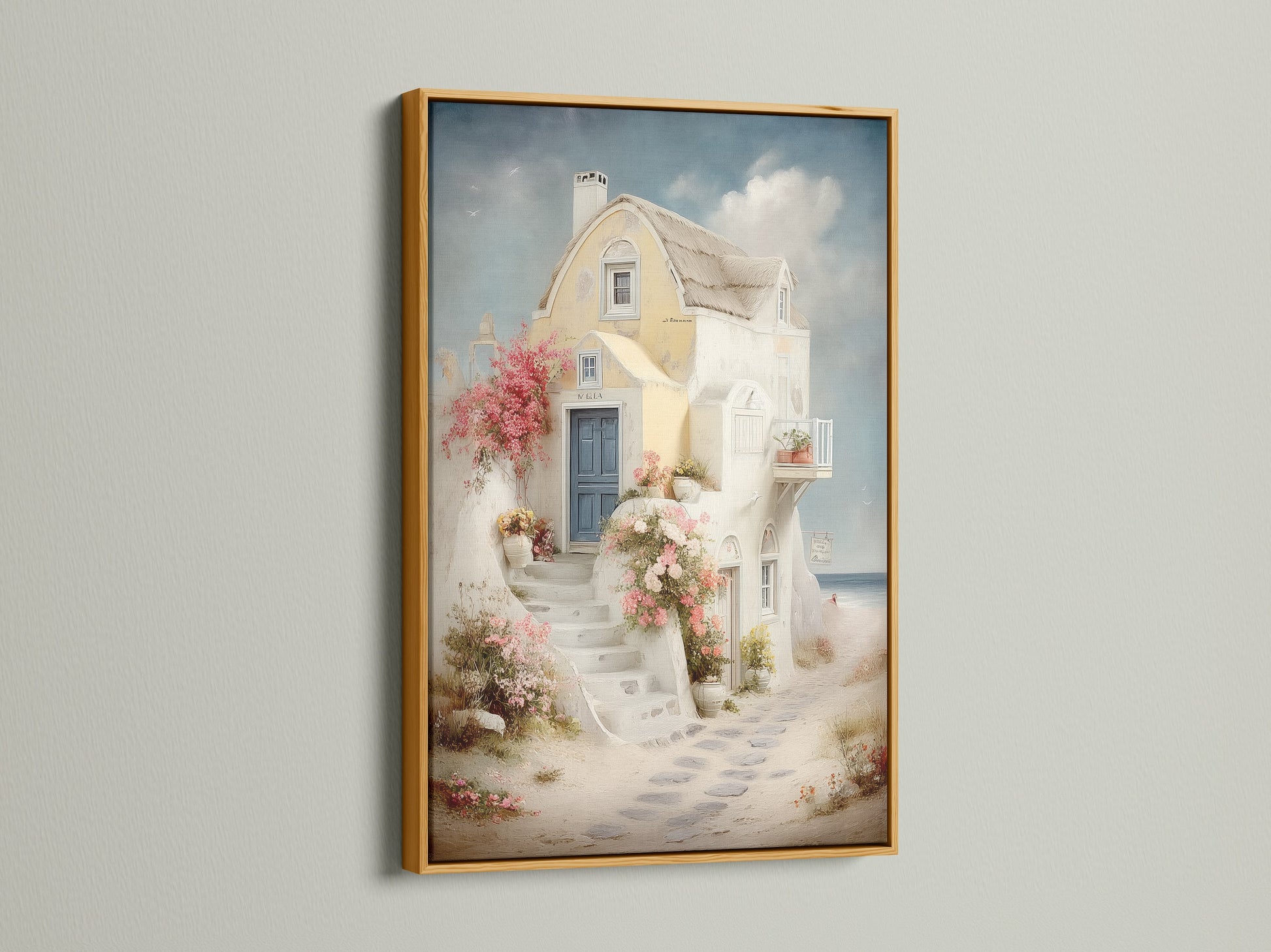 Framed coastal artwork in a gold frame. The artwork shows a Santorini-style house canvas with a blue door and floral stairway. Perfect for adding a touch of Greek island art to your vacation home decor. Ideal for bedroom wall decor.