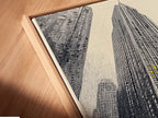 A close-up angled view displays a canvas print in a floating frame. The artwork features an urban cityscape. The modern skyscraper print adds depth and sophistication to any wall. Perfect for contemporary spaces and urban decor.